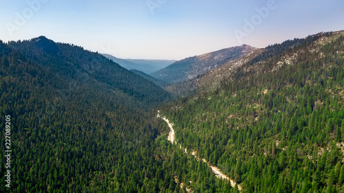 Drone view of the Eldorado National Forest and its valley with road crossing the wood uphill heading towards lake Tahoe