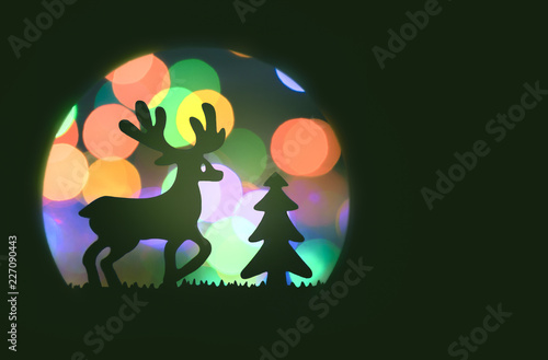 christmas closeup of reindeer near a pine tree on a colorful green bokeh background