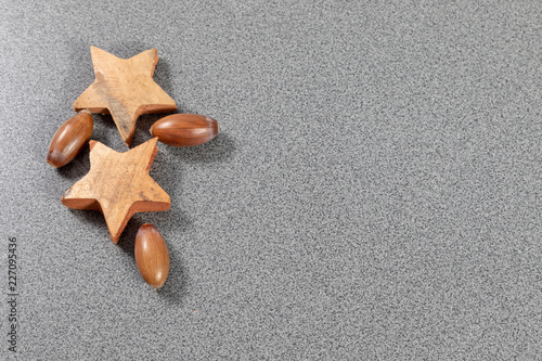 Wooden stars and acorns with copyspace on grey background