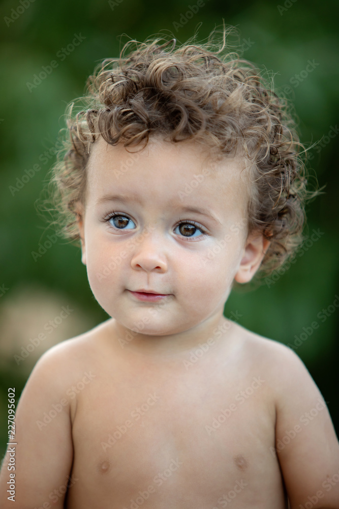 Beautiful baby with curly hair in the garden Beautiful baby with curly hair in the garden