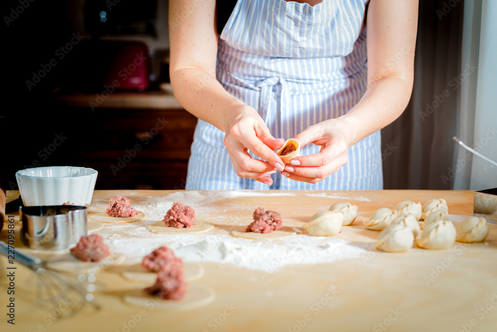 Making dough by female hands on wooden table