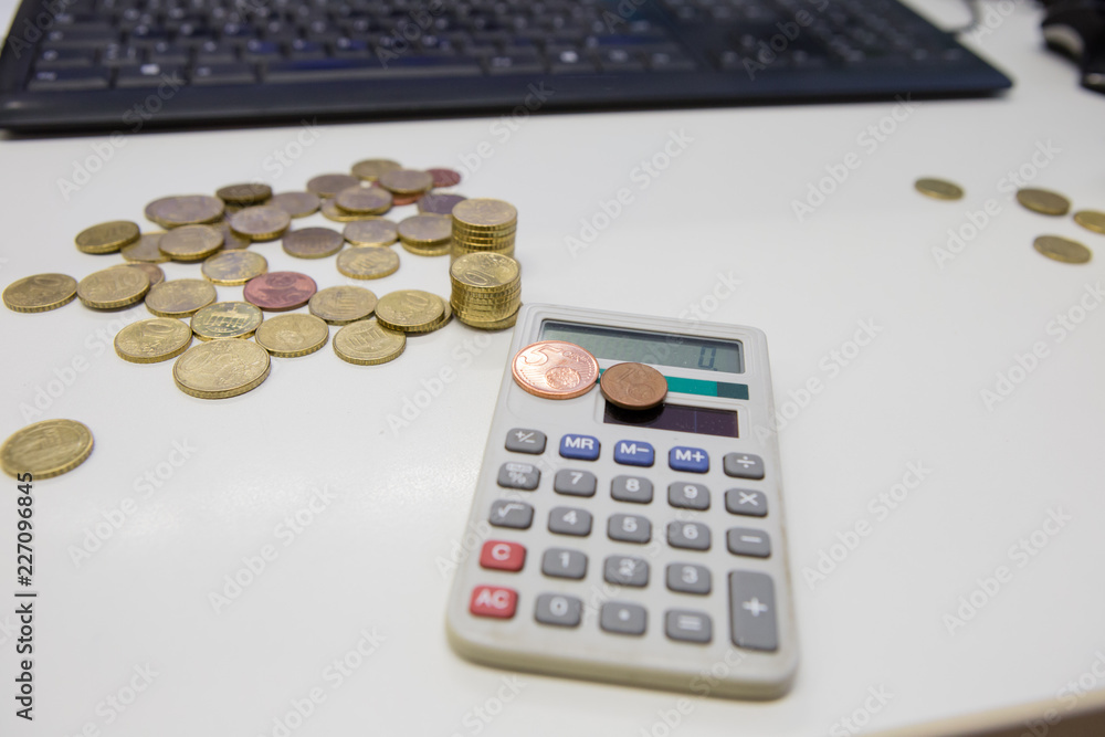 Kleingeld mit Taschenrechner und Tastatur im Hintergrund