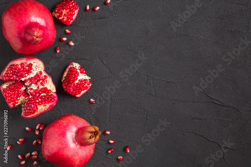 Ripe red pomegranate closeup photography on black background with copy space.