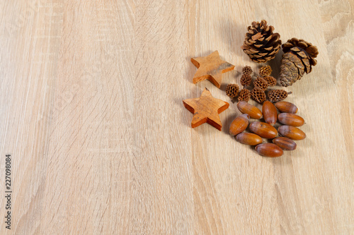 Pine cones acorns ans wooden stars with copyspace as background