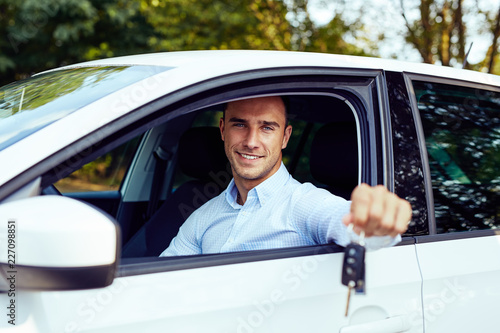 Smiling man sitting in his car and holding keys