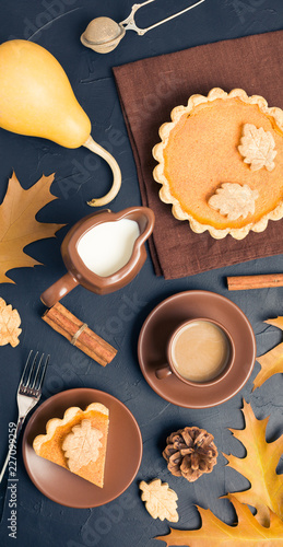 Piece of pumpkin pie with cinnamon and coffee with milk in brown dishes on black background with autumn yellow leaves. © Yuliia Osadcha
