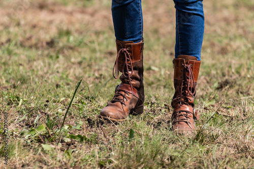 Beautiful slim legs in tight blue jeans. Country cow girl with brown leather boots walking on dry grass, end of season moments. Farm life, stylish woman.. © Edward R