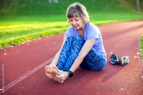 Fitness, sport, exercising and healthy lifestyle concept - young woman with injured leg outdoors