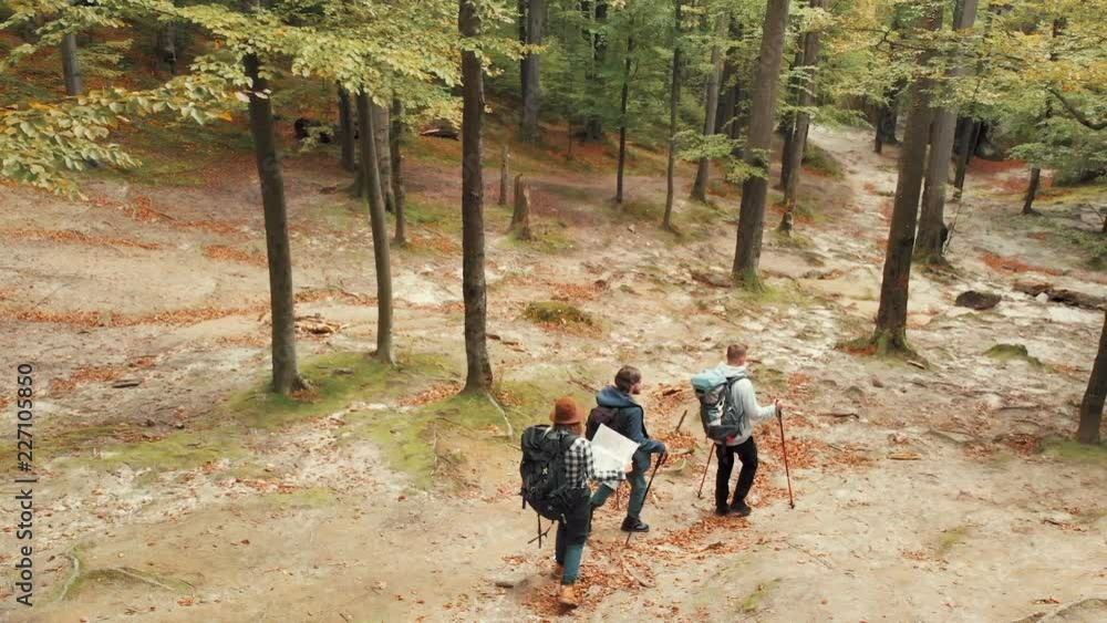 Group of friends going down the hill, trying to find the way back with the help of map, drone shot in gorgeous rocky location Group of friends going down the hill, trying to find the way back with the help of map, drone shot in gorgeous rocky location