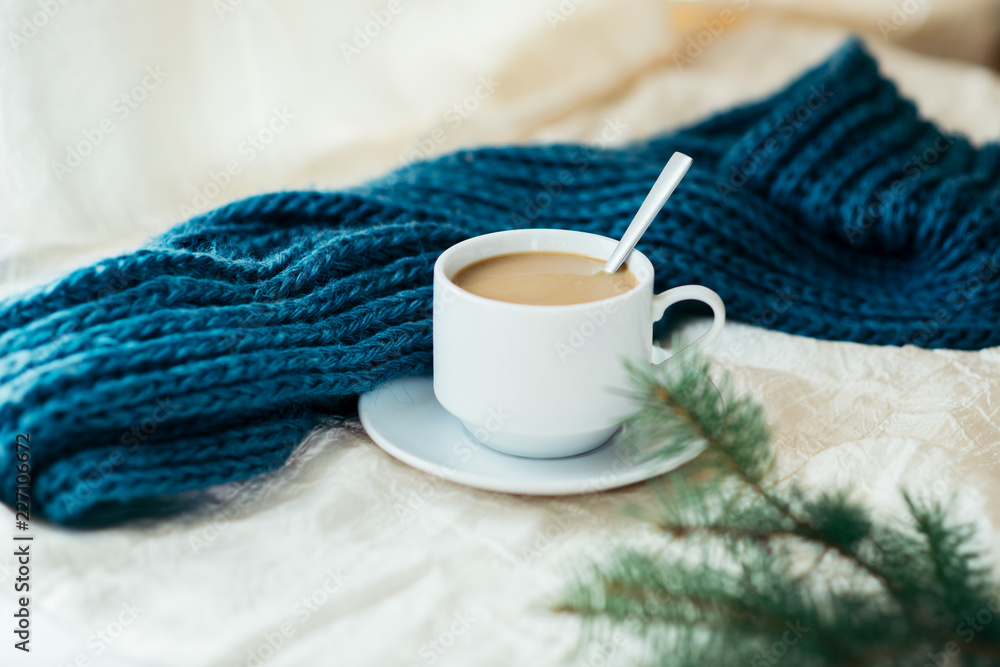 cup of tea with milk on a textile background with a knitted sweater and needles. cup of tea with milk on a textile background with a knitted sweater and needles.