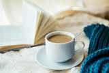 cup of tea with milk on a textile background with a knitted sweater and  needles.