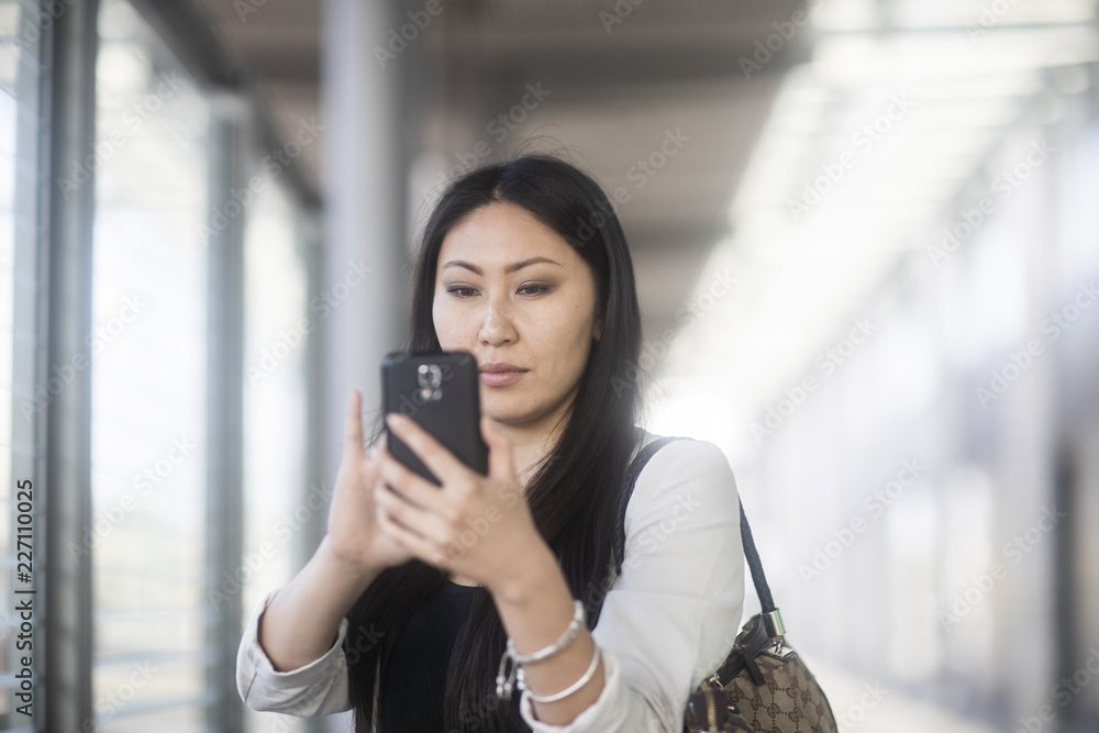 Junge Frau Asiatin kauft Ticket am Bahnhof mit Smartphone