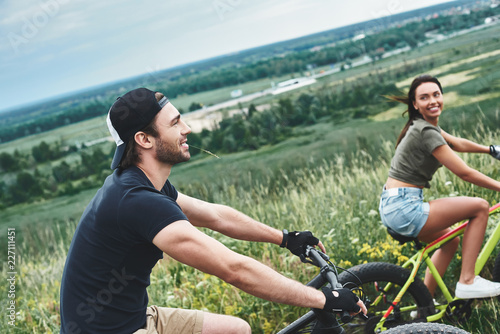 A man and a woman are laughing and cycling. Close up view