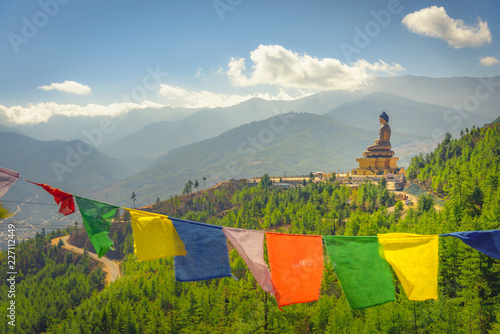 Paro Buddha with prayer flags in foreground and the valley in the background