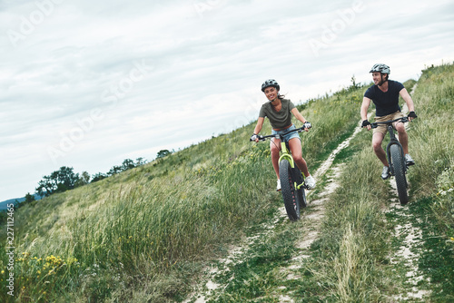 Young couple are cycling on fatbikes and in helmets © Friends Stock