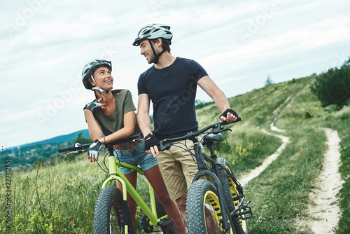 Young couple are flirting with each other and driving their fatbikes in helmets