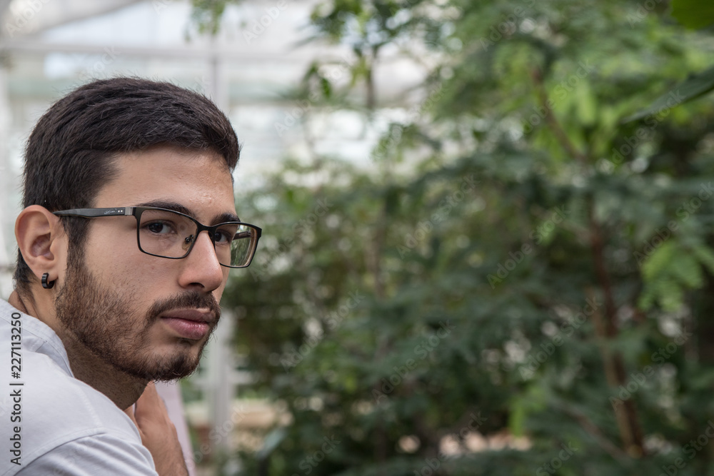 portrait of young man with glasses in a greenhouse portrait of young man with glasses in a greenhouse