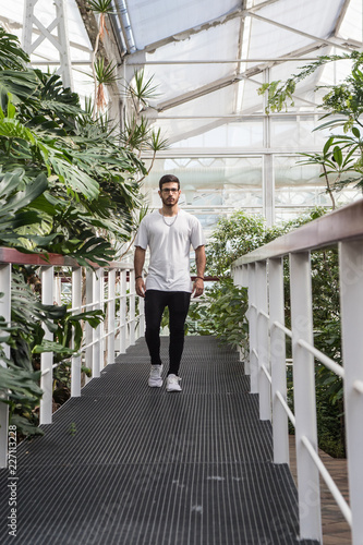 young man walking down a catwalk surrounded by plants
