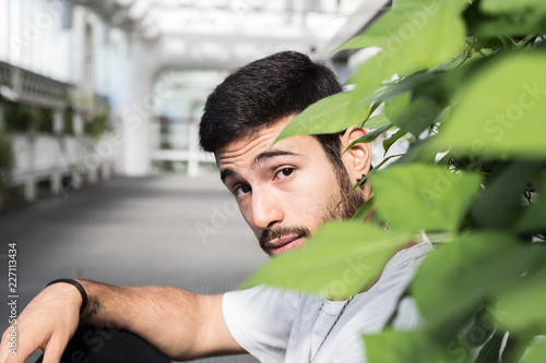 portrait of young man among green leaves