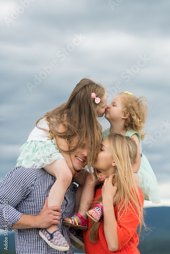 Girls kiss on mother father shoulders on cloudy sky © Volodymyr