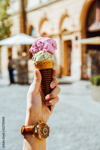 Woman Holding Green Pistachio And Pink Raspberry Ice Cream Cone In Hand