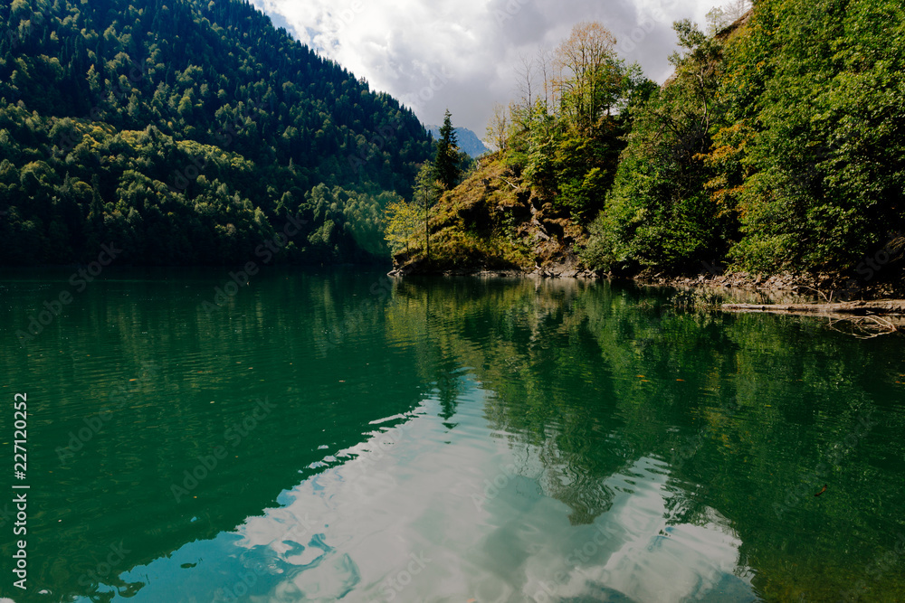 Transparent turquoise lake in the midst of autumn trees and mountains