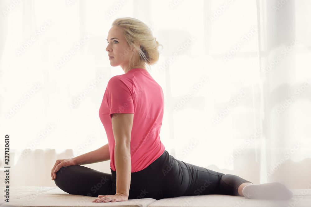 Beautiful athletic woman doing stretching exercises in front of window Beautiful athletic woman doing stretching exercises in front of window