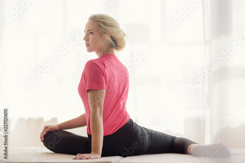 Beautiful athletic woman doing stretching exercises in front of window
