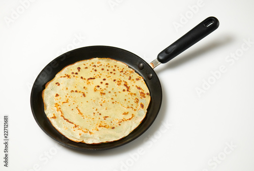 Crepe closeup, thin pancake on a frying pan, white background