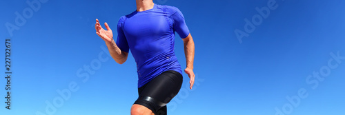 Sport runner male athlete running in compression sportswear clothing outdoor on blue background. Panoramic banner of man on run race. photo