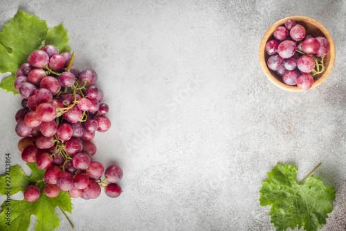 Red grapes with leaves of grapes on a stone table. Top view. Free space for text.