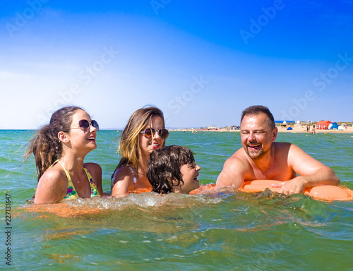 happy family with children is swimming and having fun in the sea on an inflatable mattress. happy friendly family concept