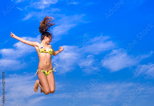 Attractive Girl in Bikini Jumping on the Beach Having Fun, Summer vacation holiday Lifestyle. Happy women jumping freedom on sand. © kravik93