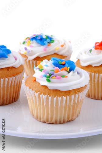 Frosted Vanilla Cupcakes With Sprinkles On A Plate
