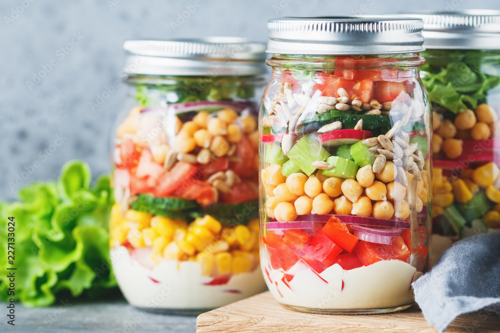 Three glass jars with layering various vegan salads for healthy lunch. The concept of fitness and vegetarian food. Three glass jars with layering various vegan salads for healthy lunch. The concept of fitness and vegetarian food.