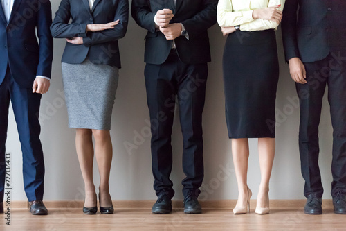 Legs of diverse work team pose for corporate photoshoot or make picture, job applicants in suits standing in row, waiting for recruiting talk or interview results. HR, hiring, employment concept