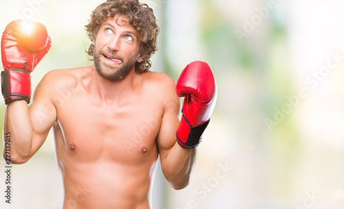 Handsome hispanic boxer man wearing boxing gloves over isolated background sticking tongue out happy with funny expression. Emotion concept.
