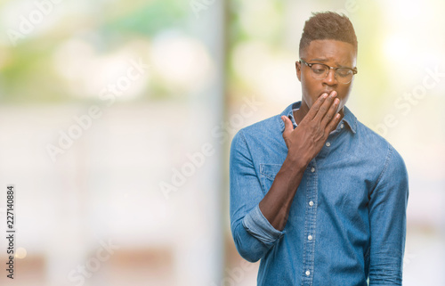 Young african american man over isolated background bored yawning tired covering mouth with hand. Restless and sleepiness.