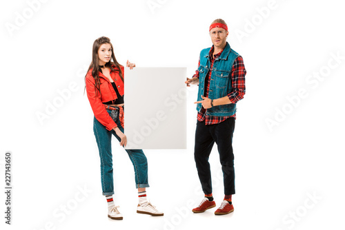 young male hipster pointing at empty banner while his girlfriend standing near isolated on white