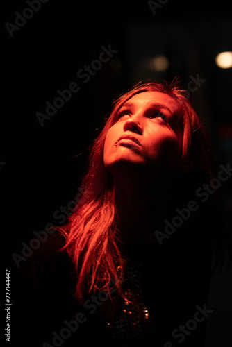 Portrait of girl with reflection of herself looking up on red lights