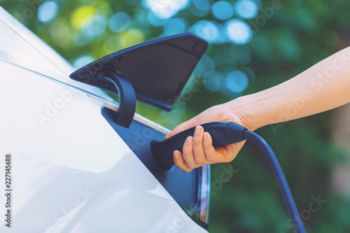 Obraz na plátně Person charging an electric vehicle with green background
