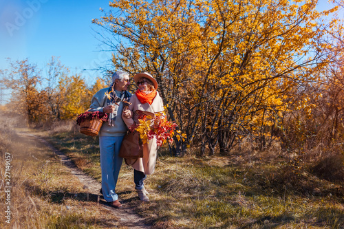Senior couple walking in autumn forest. Middle-aged man and woman hugging and chilling outdoors