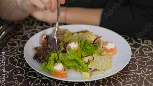 Wallpaper Mural A plate with Caesar salad on the table. A woman with a fork is eating a salad Torontodigital.ca