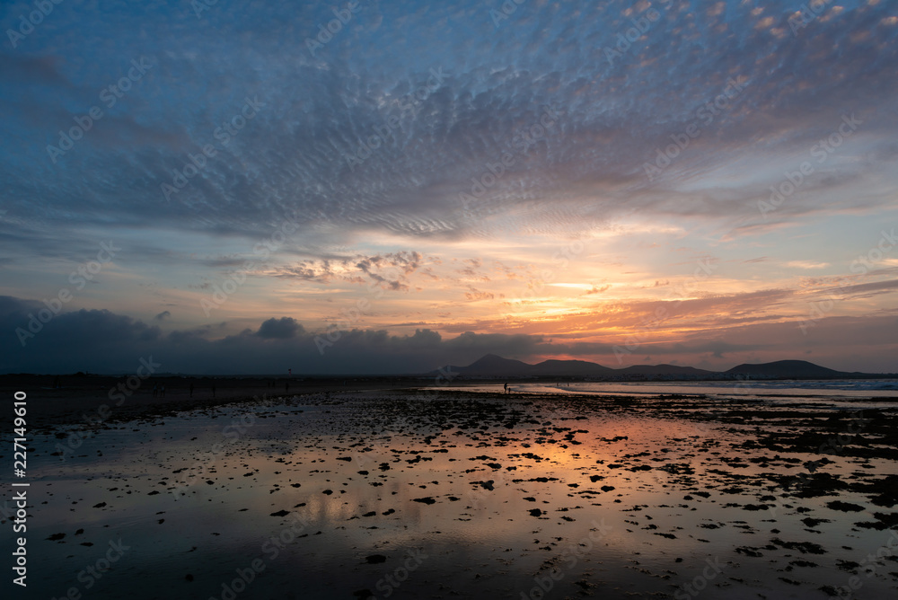 Obraz premium Amazing sunset with pockmarked sky shot on a sandy beach at low tide