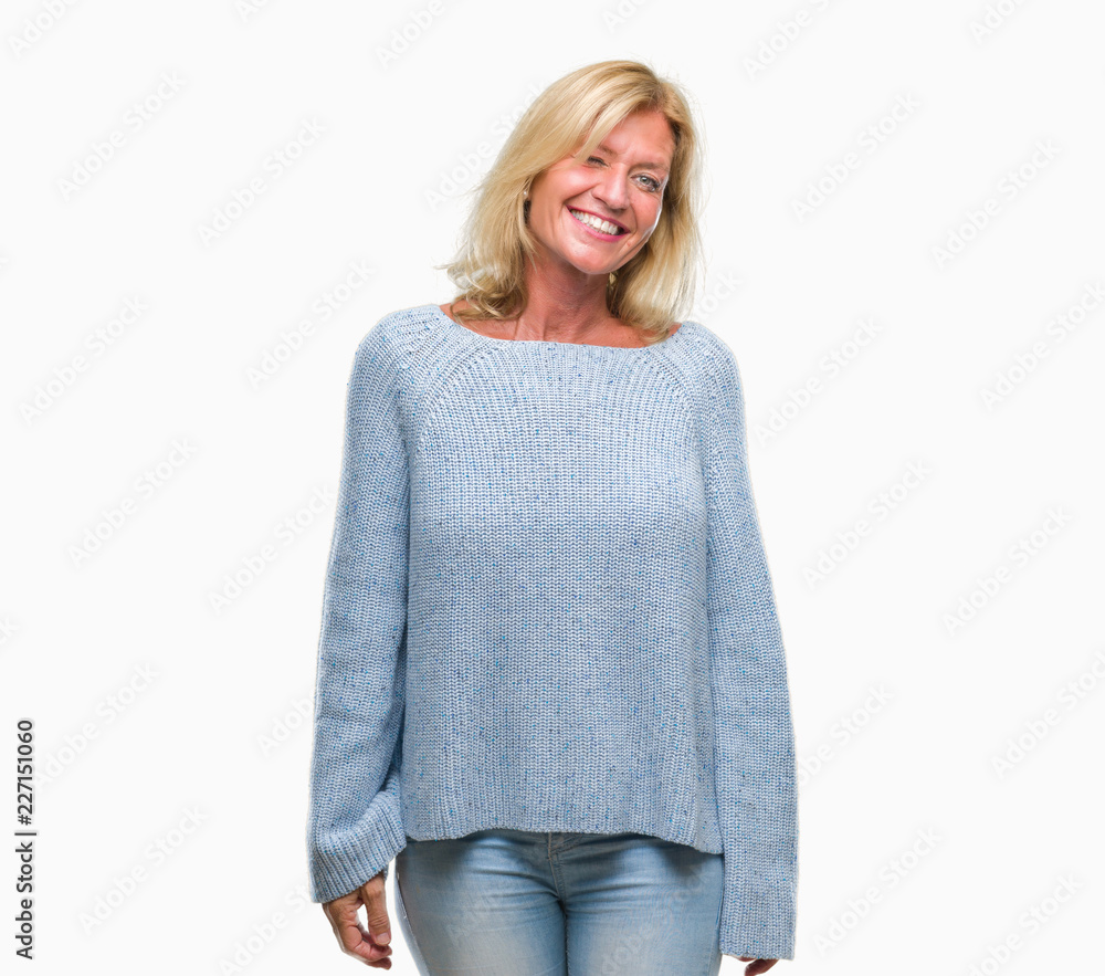 Middle age blonde woman wearing winter sweater over isolated background winking looking at the camera with sexy expression, cheerful and happy face. Middle age blonde woman wearing winter sweater over isolated background winking looking at the camera with sexy expression, cheerful and happy face.