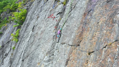 Aerial footage Close up of young female climber preparing on the side of a cliff in Maine photo