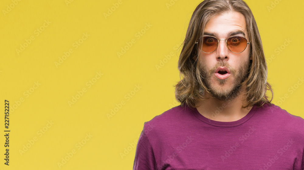 Young handsome man with long hair wearing sunglasses over isolated background afraid and shocked with surprise expression, fear and excited face. Young handsome man with long hair wearing sunglasses over isolated background afraid and shocked with surprise expression, fear and excited face.