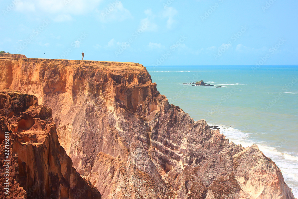 Man on top of cliffs over Arapuca Beach, ocean on the background