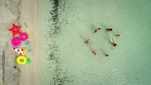 Aerial view of friends playing volleyball standing in sea by sandy beach with inflatable matresses. photo