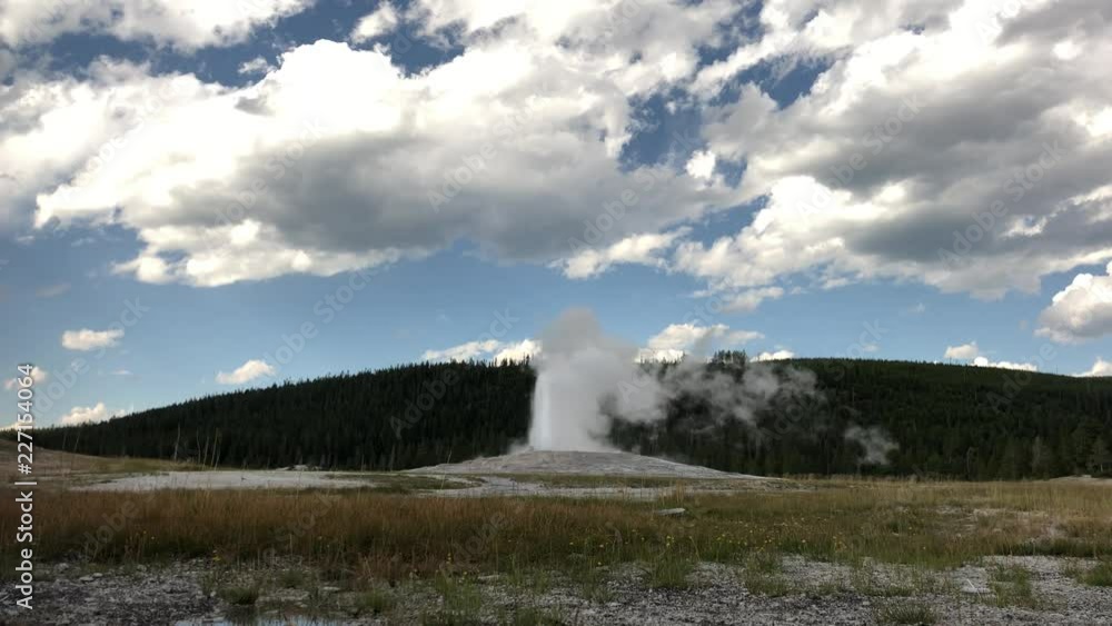 Old Faithful geyser during one of its regular eruptions, with gorgeous clouds in the skies Old Faithful geyser during one of its regular eruptions, with gorgeous clouds in the skies